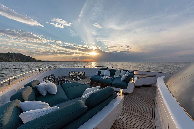 a deck with a view of the ocean and the sun setting aboard JAKAT Yacht for Sale