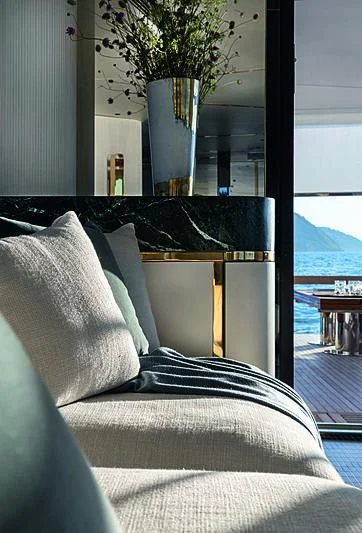 a couch with pillows and a vase of flowers on it aboard JAKAT Yacht for Sale