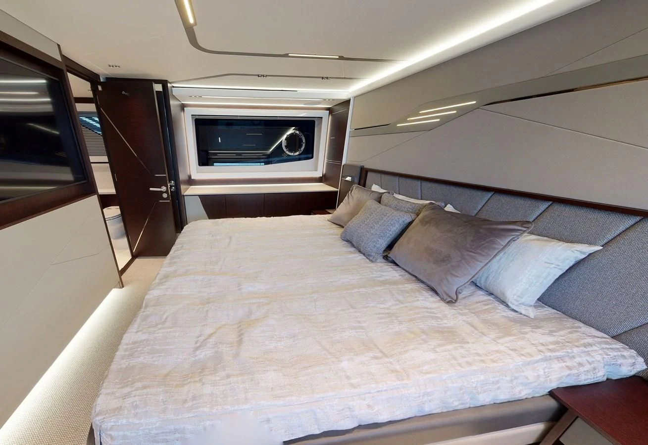 a bed with a white sheet and a television on the wall aboard FIVE II Yacht for Sale