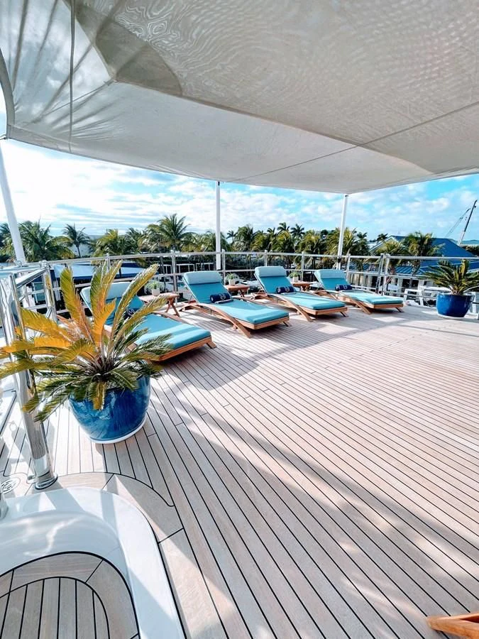 a deck with a pool and a deck with chairs and trees aboard NEXT CHAPTER Yacht for Sale