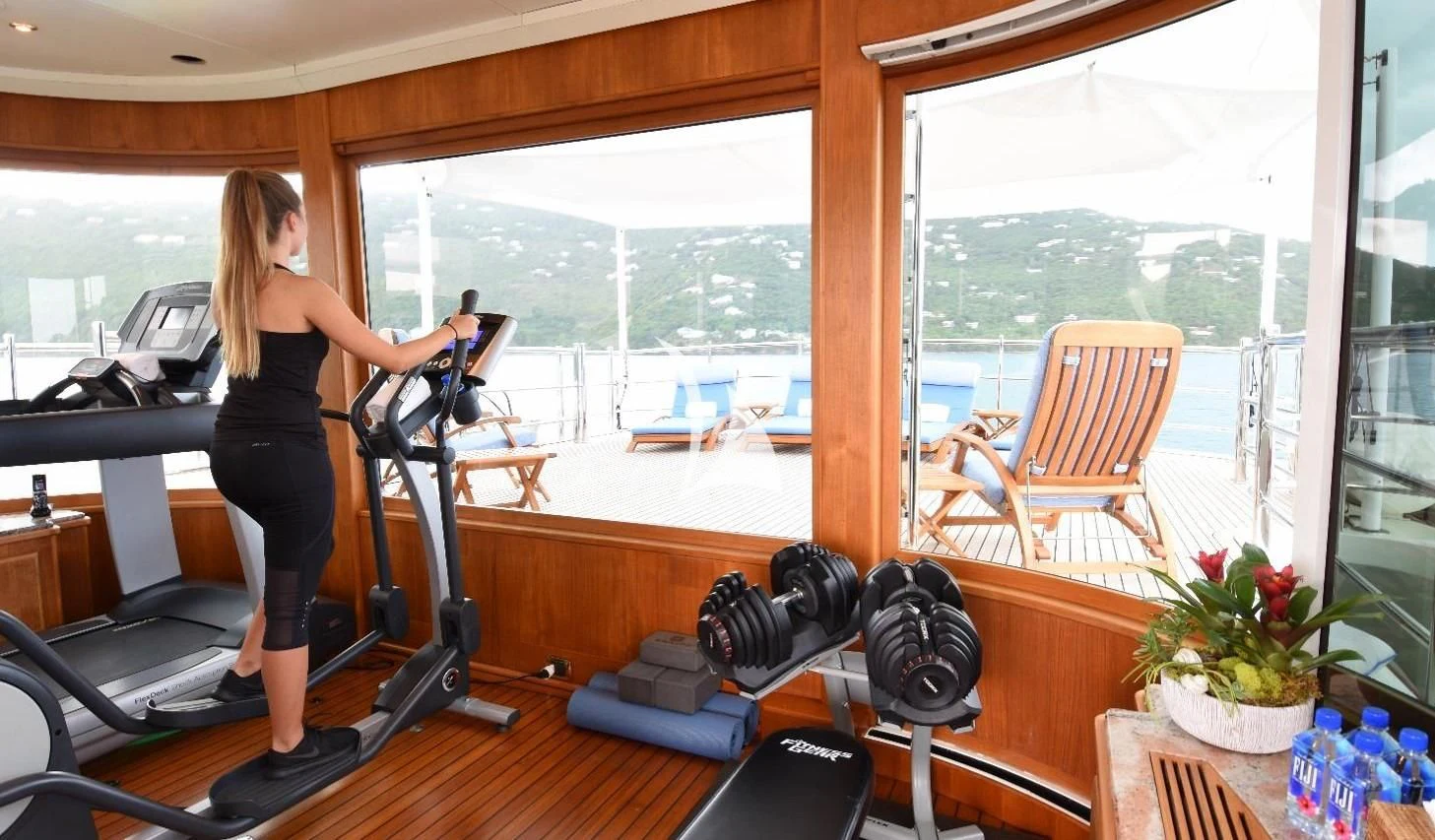 a person standing in a room with a large window and a table with chairs and a planter aboard NEXT CHAPTER Yacht for Sale