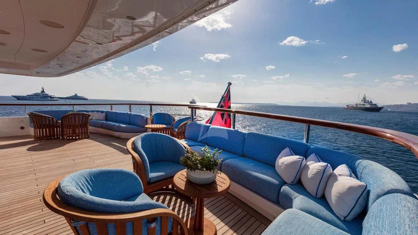a lounge area with a large body of water and a large ship in the background aboard NEXT CHAPTER Yacht for Sale