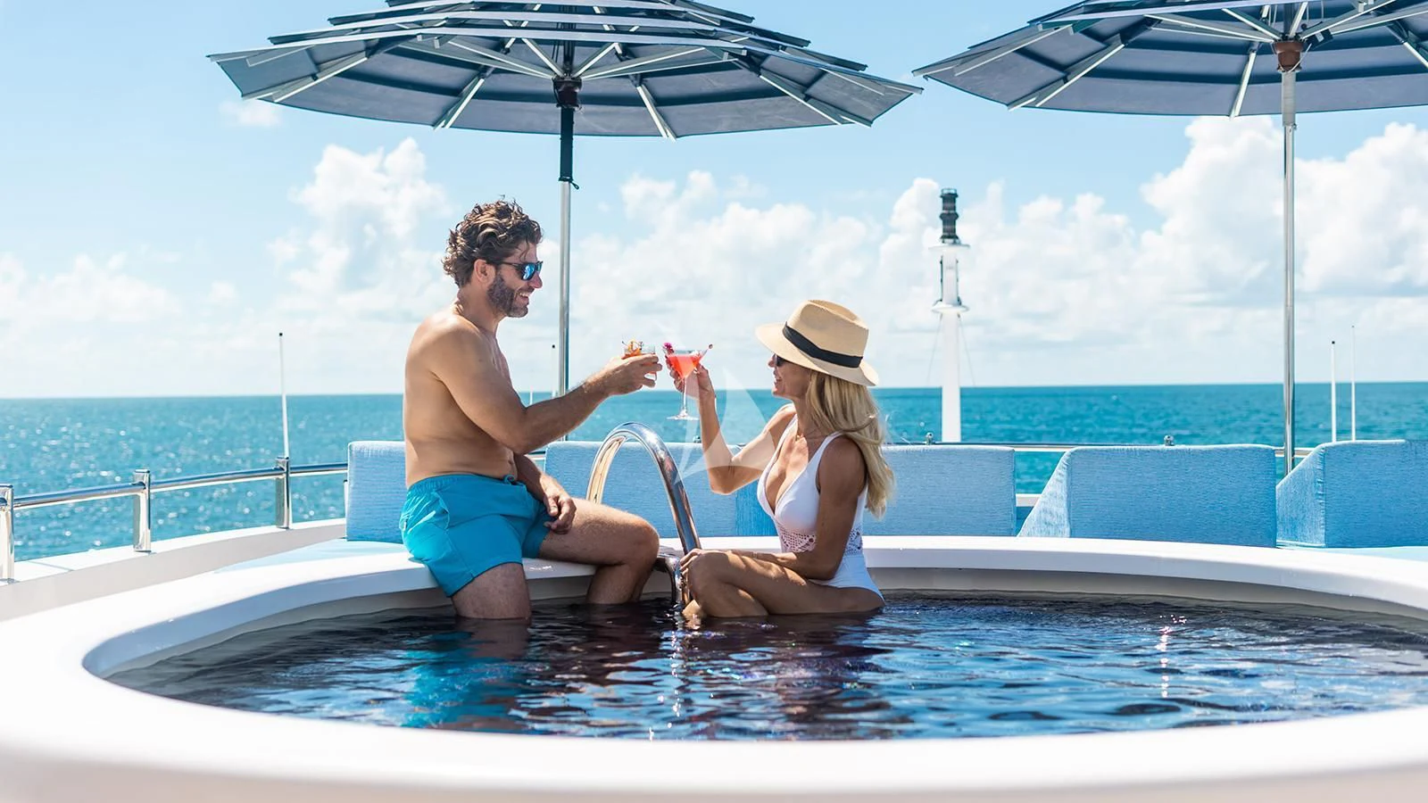 a man and woman sitting in a pool with umbrellas aboard NEXT CHAPTER Yacht for Sale