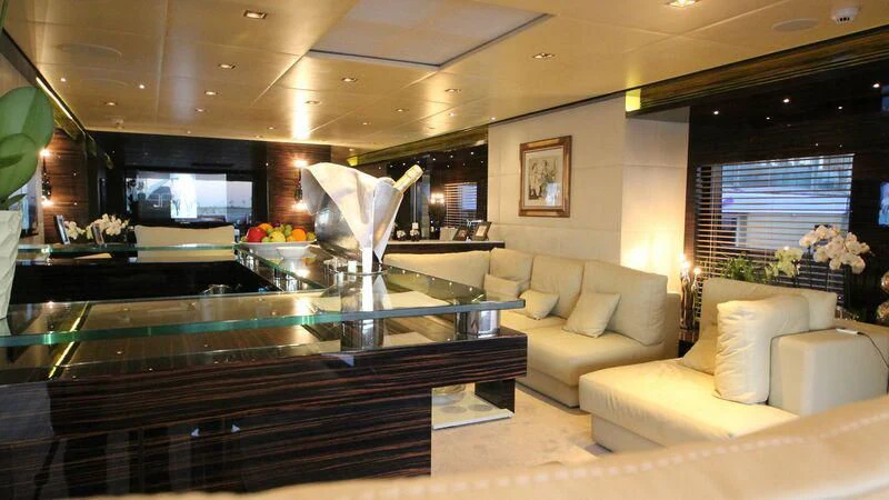 a living room with a large glass table and couches aboard OCEAN CLUB Yacht for Sale