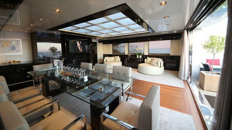a room with a large screen and a table with chairs and a tv aboard OCEAN CLUB Yacht for Sale