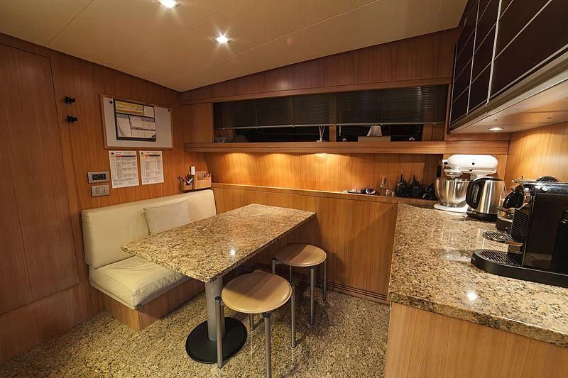 a kitchen with a table and stools aboard FASTER Yacht for Sale