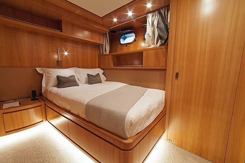 a room with a bed and a wood wall aboard FASTER Yacht for Sale