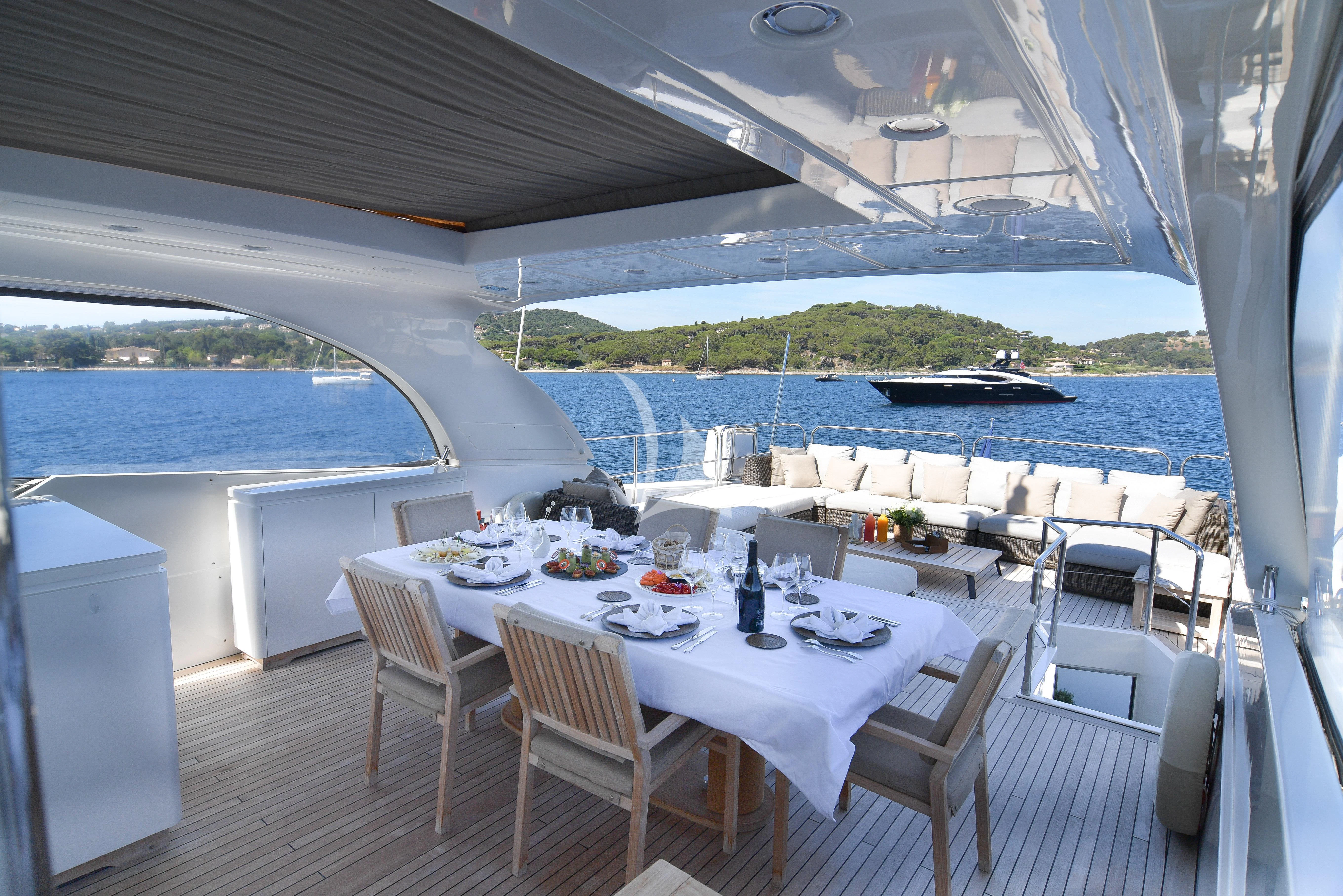 a table set for a meal on a balcony overlooking a body of water aboard FASTER Yacht for Sale