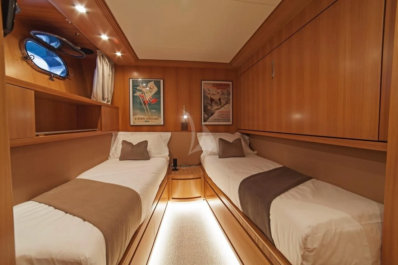 a room with beds and a mirror aboard FASTER Yacht for Sale