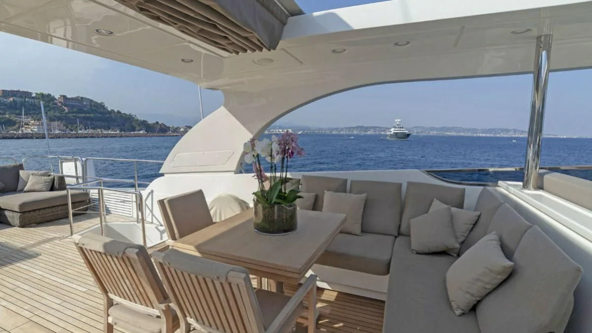 a table and chairs on a deck overlooking a body of water aboard FASTER Yacht for Sale