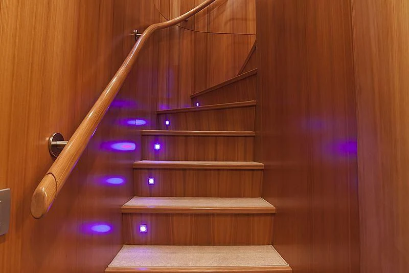 a wooden staircase with lights aboard FASTER Yacht for Sale