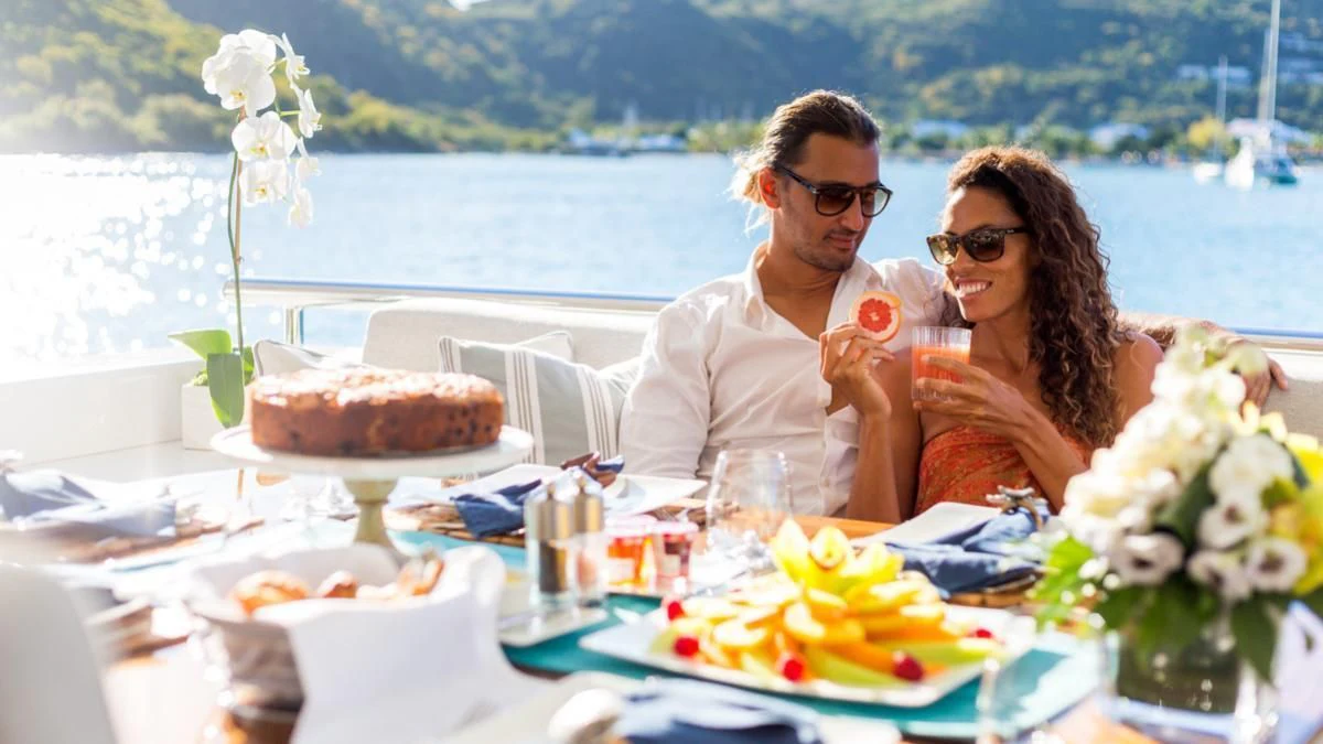 a man and woman sitting at a table with a cake and flowers aboard KING BABY Yacht for Sale