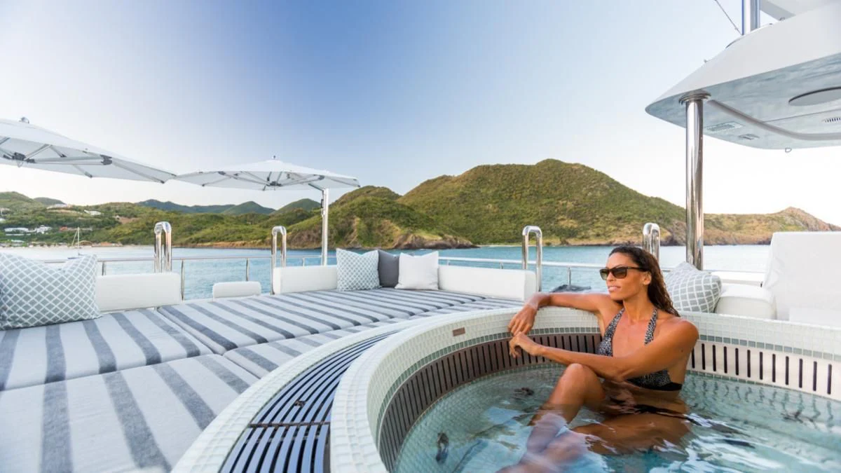 a woman sitting on a lounge chair on a deck of a boat aboard KING BABY Yacht for Sale