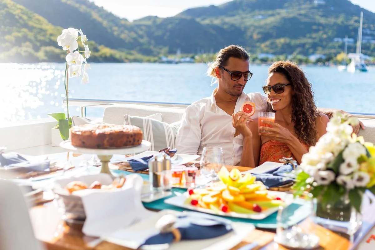 a man and woman sitting at a table with a cake and flowers aboard KING BABY Yacht for Sale