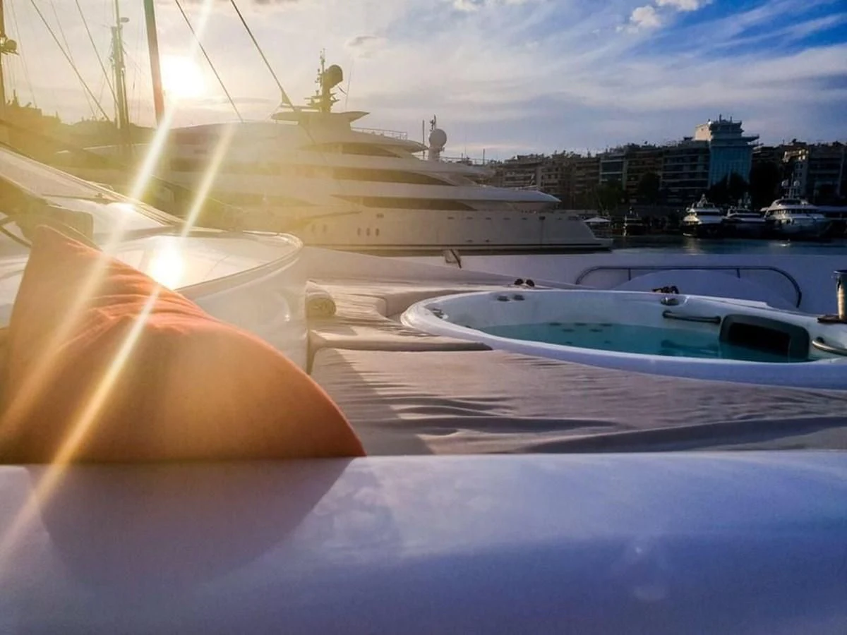 a person's hand on a window sill with a boat and city in the background aboard AURORA Yacht for Sale