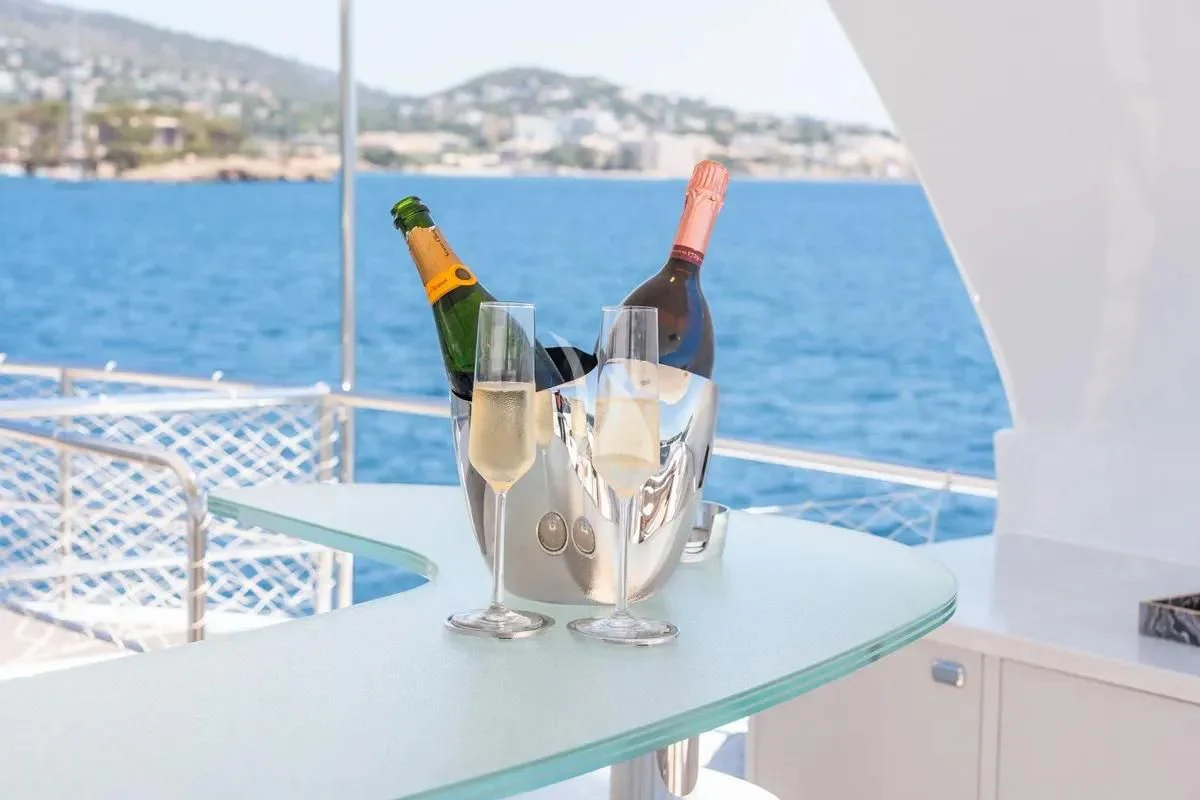 a bottle of champagne and glasses on a table with a glass of champagne aboard TITIAN PEARL Yacht for Sale