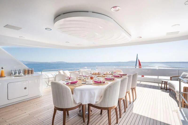 a dining room with a large white table and chairs and a large body of water aboard TITIAN PEARL Yacht for Sale