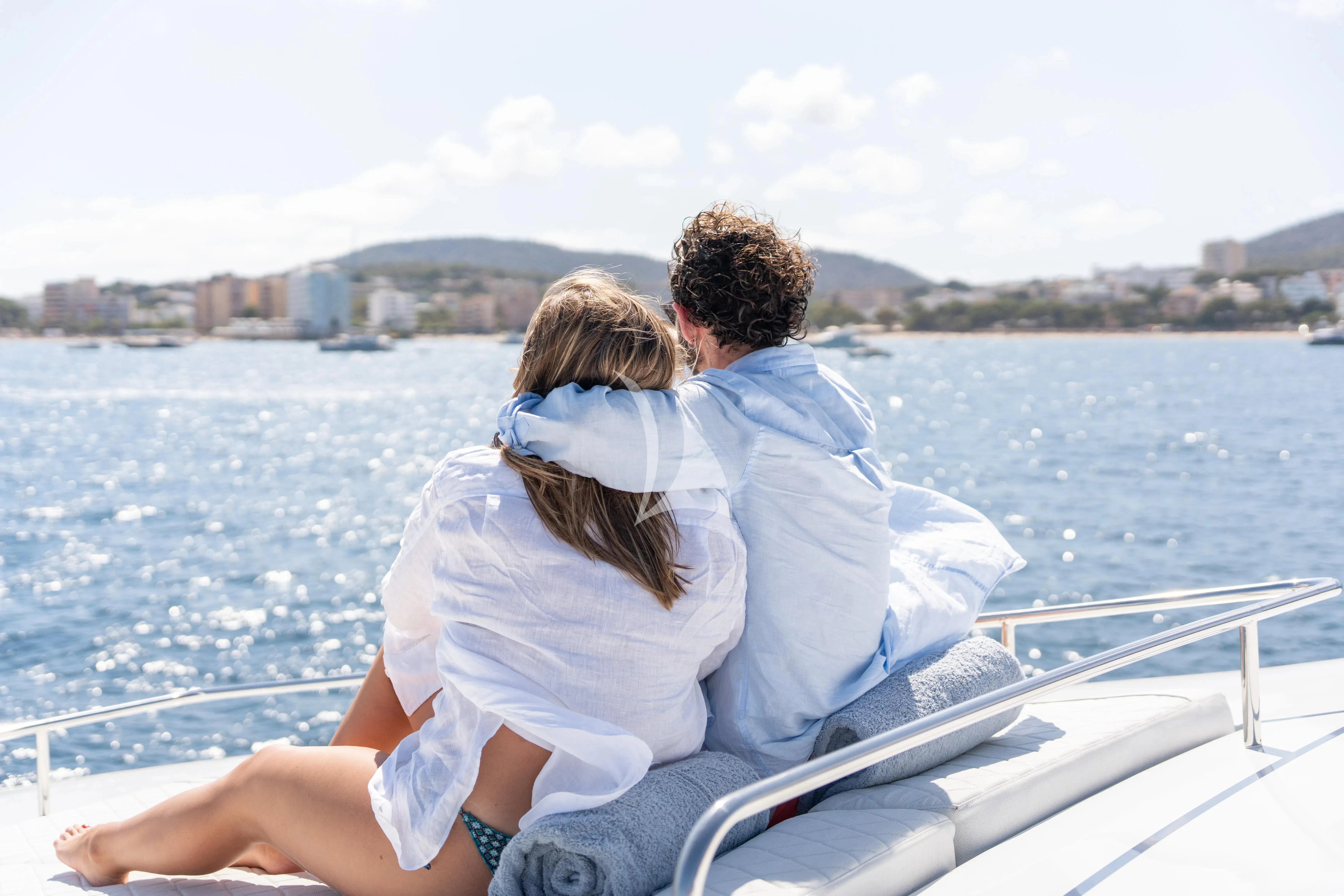 a man and woman sitting on a boat with a city in the background aboard TITIAN PEARL Yacht for Sale