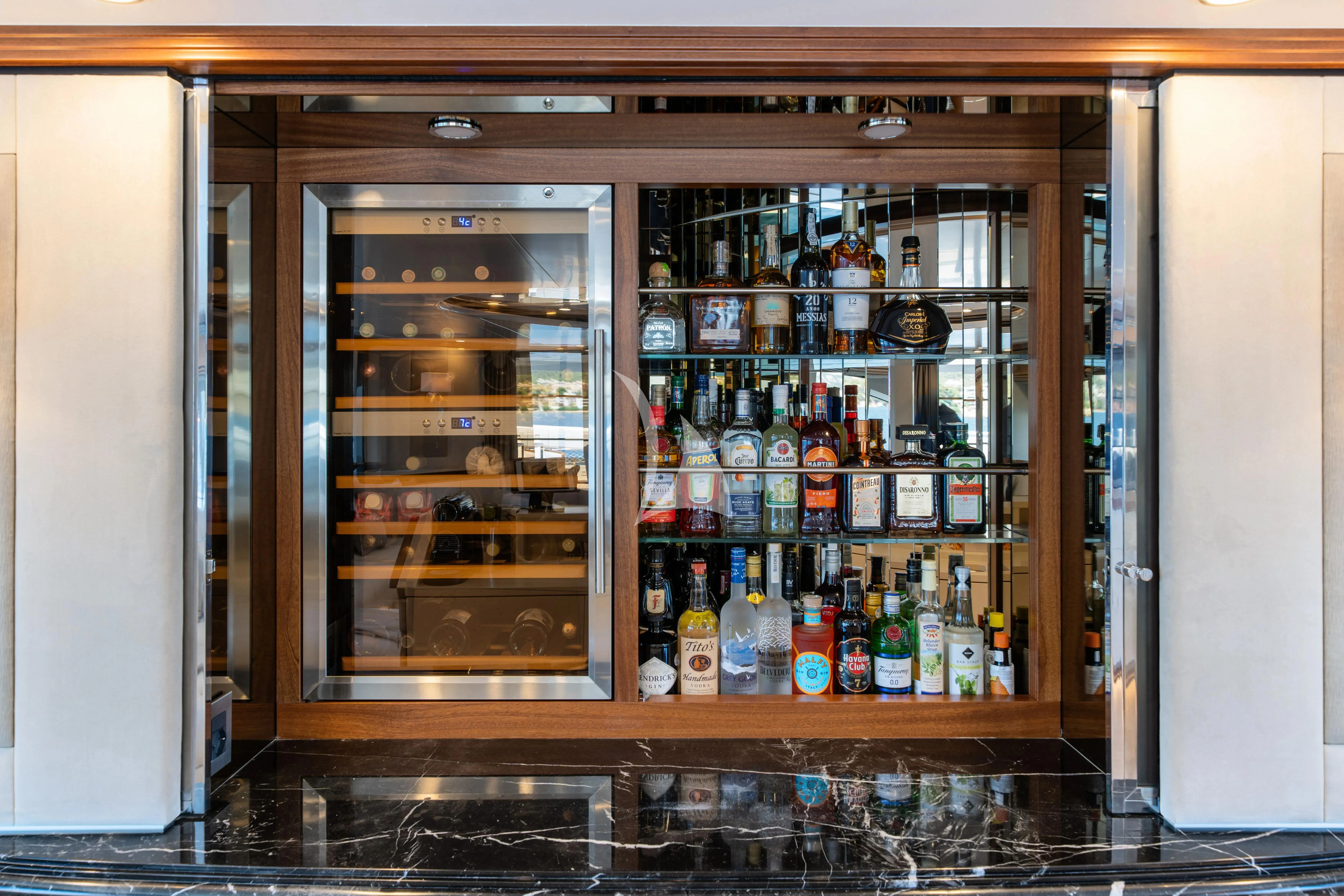a glass case with a variety of beverages and bottles in it aboard TITIAN PEARL Yacht for Sale