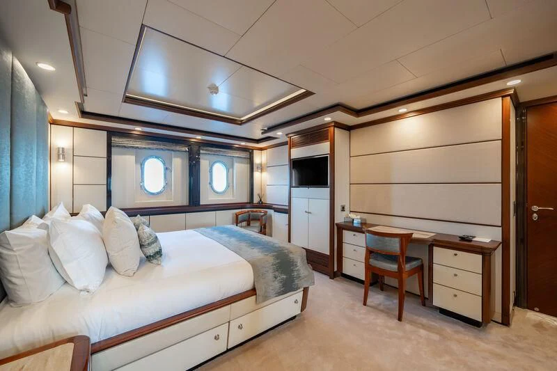 a bedroom with a bed and desk aboard TITIAN PEARL Yacht for Sale
