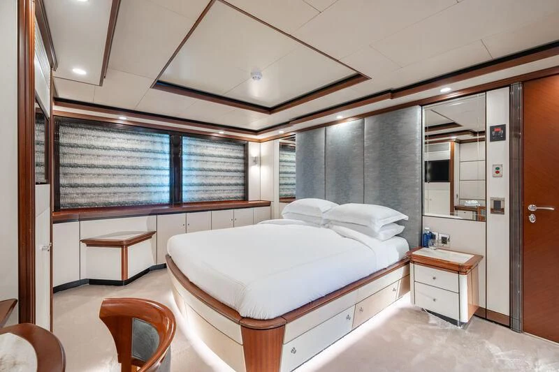 a room with a bed and a desk aboard TITIAN PEARL Yacht for Sale