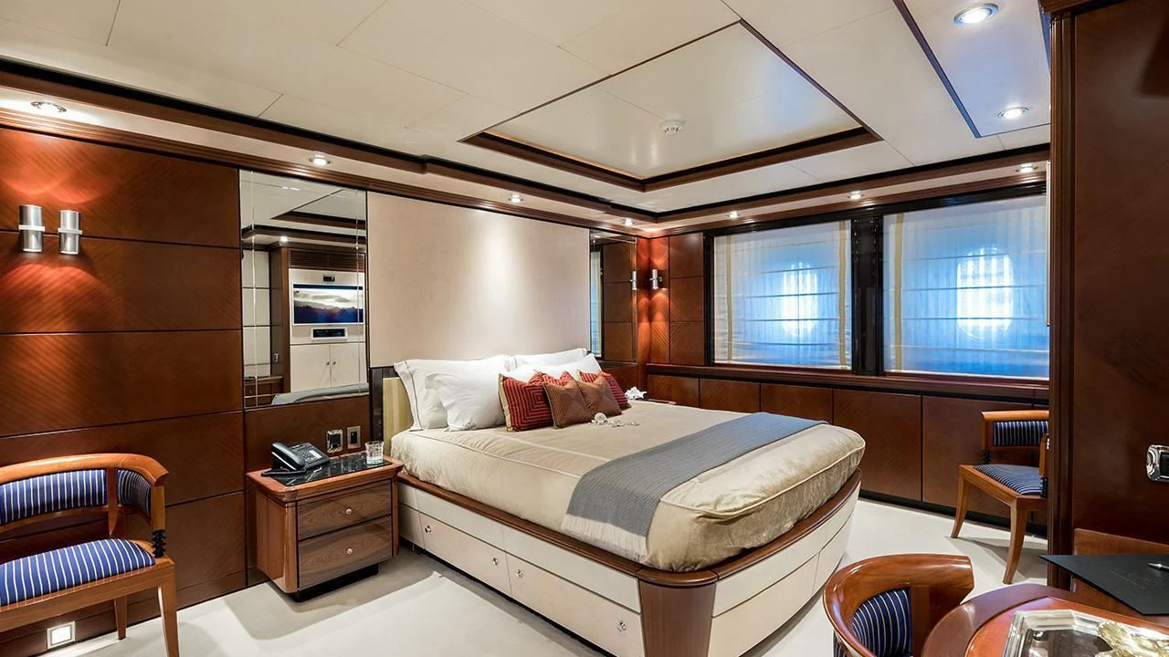 a bedroom with a bed and a desk aboard TITIAN PEARL Yacht for Sale