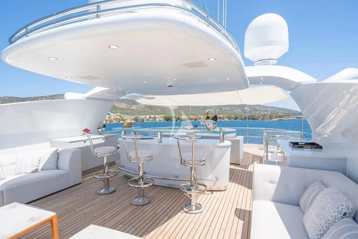 a large white building with a round table and chairs and a large white umbrella on a sunny day aboard TITIAN PEARL Yacht for Sale
