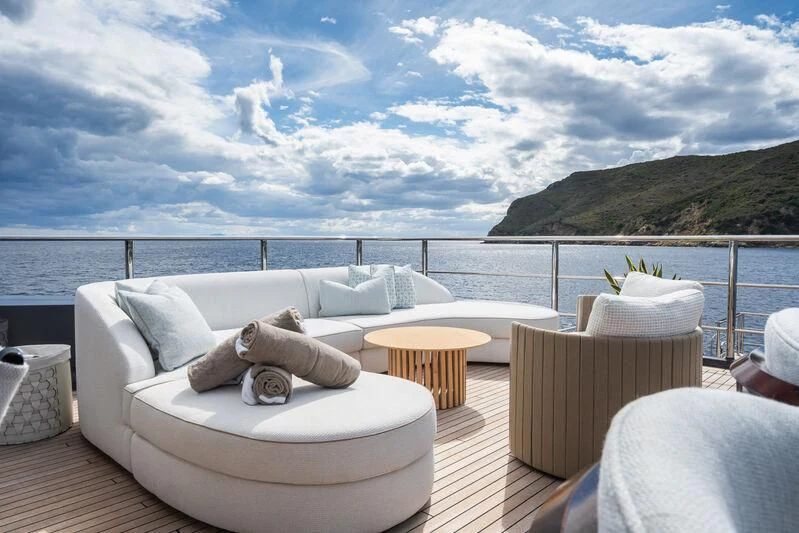 a large white lounge chair on a deck overlooking a large body of water aboard PARA BELLVM Yacht for Charter