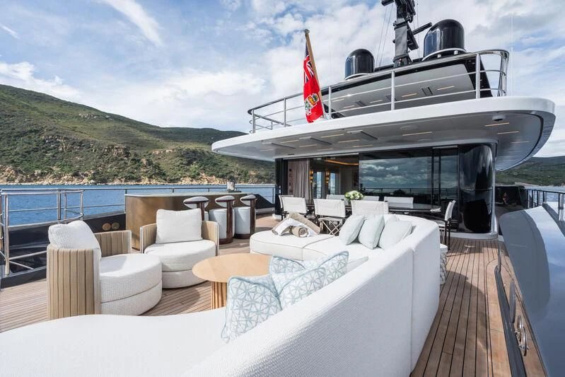 a deck with chairs and a boat on it aboard PARA BELLVM Yacht for Charter