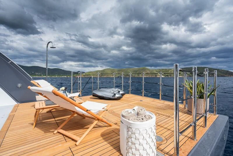a deck with a chair and a can on it and a body of water in the background aboard PARA BELLVM Yacht for Charter