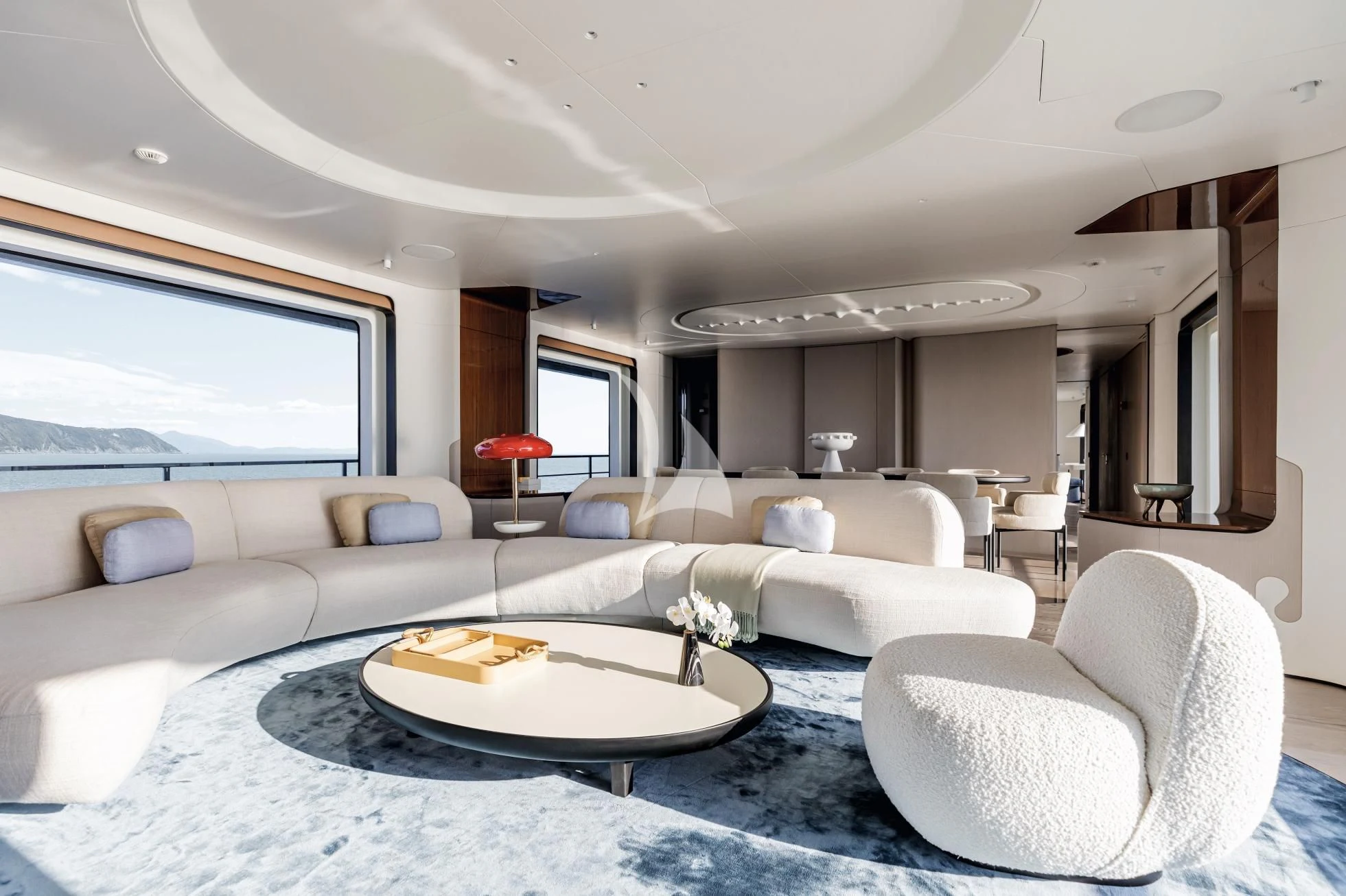 a living room with a large white couch and a round table aboard LUZ DE MAR Yacht for Sale