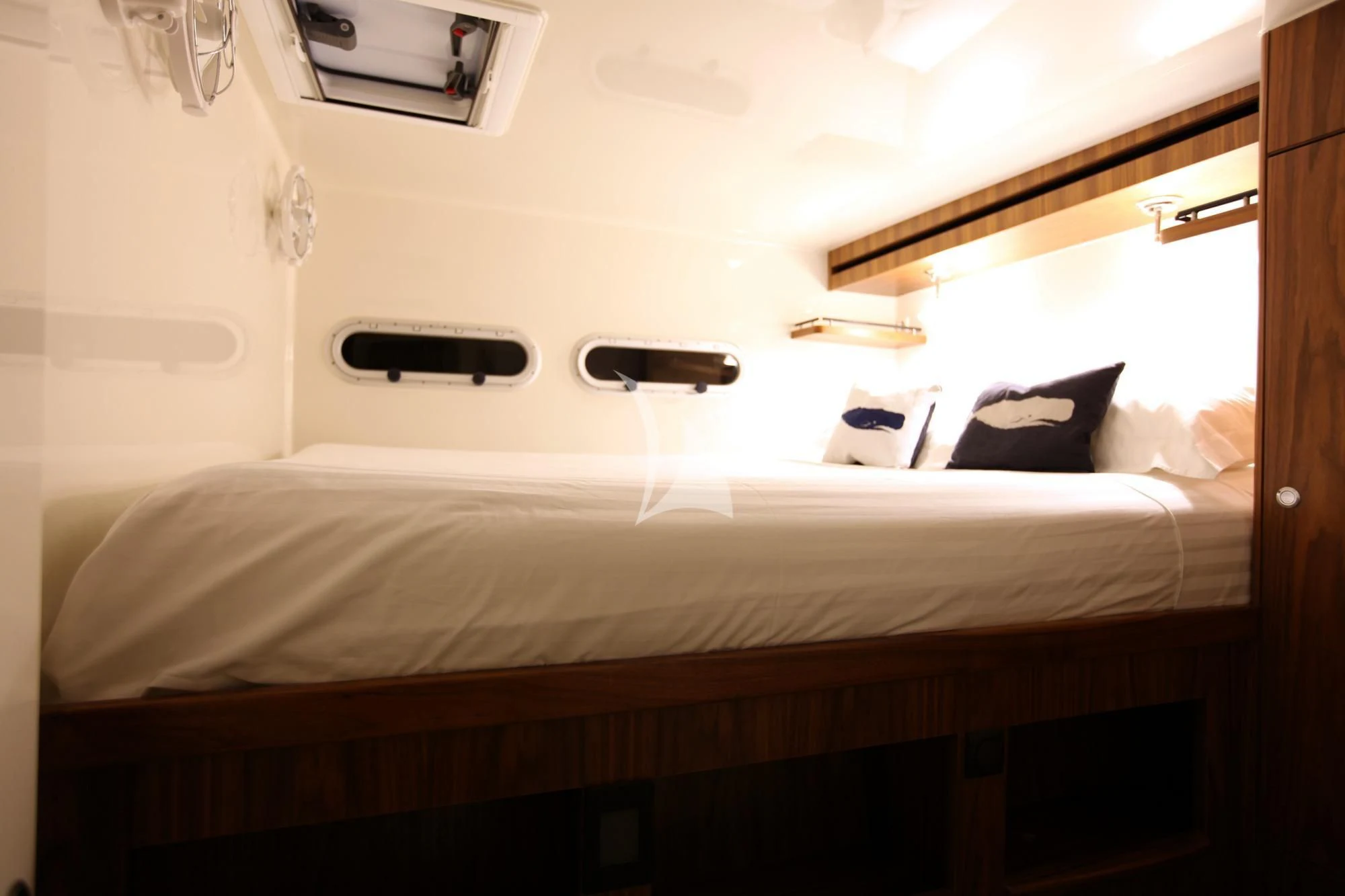 a bed with a white sheet and a black object on the side aboard SLIM Yacht for Charter