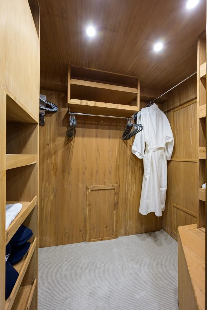 a room with a wood door and a white dress on the wall aboard RISK TAKER Yacht for Charter