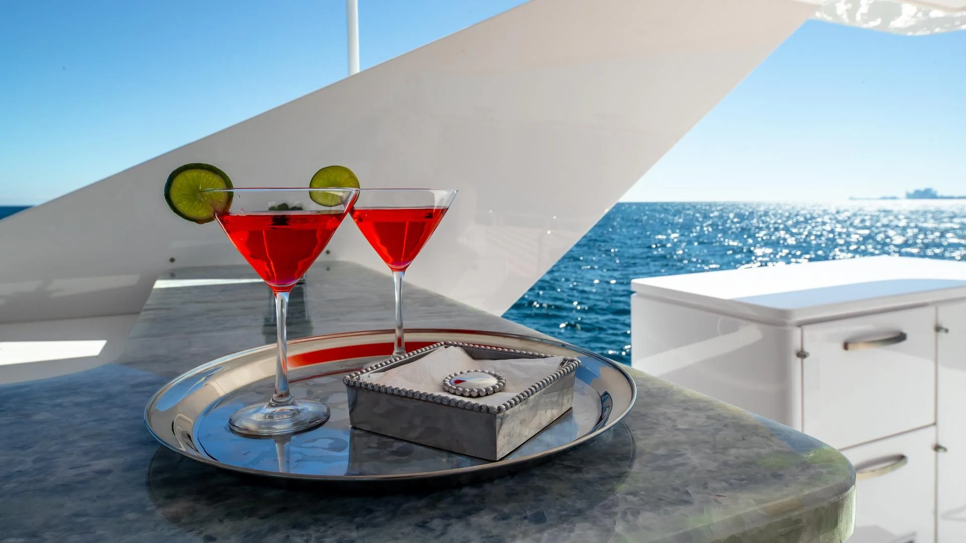 a couple of glasses of red wine on a tray next to a pool aboard RISK TAKER Yacht for Charter