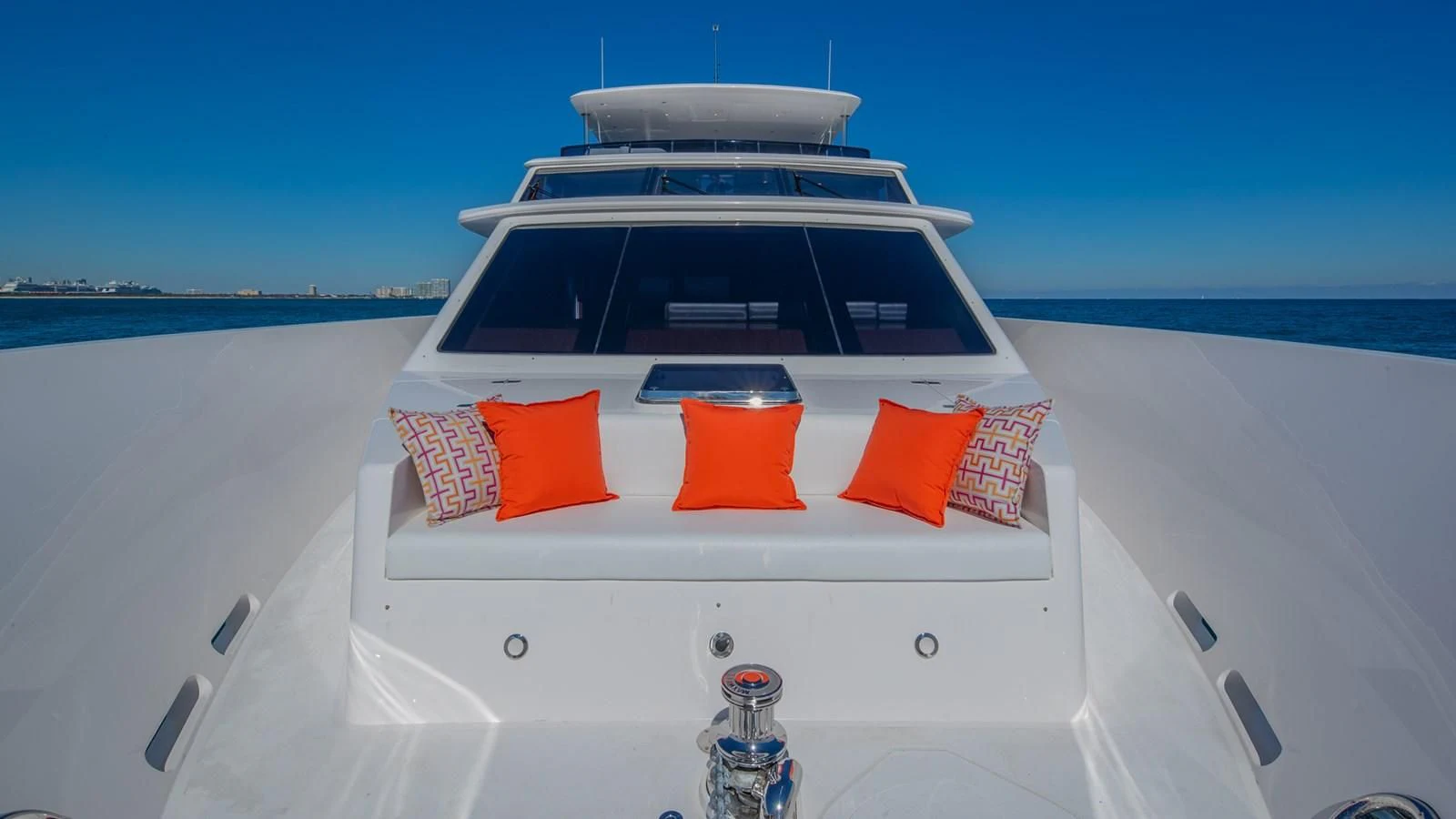 a white boat with orange and red pillows on a white surface aboard RISK TAKER Yacht for Charter