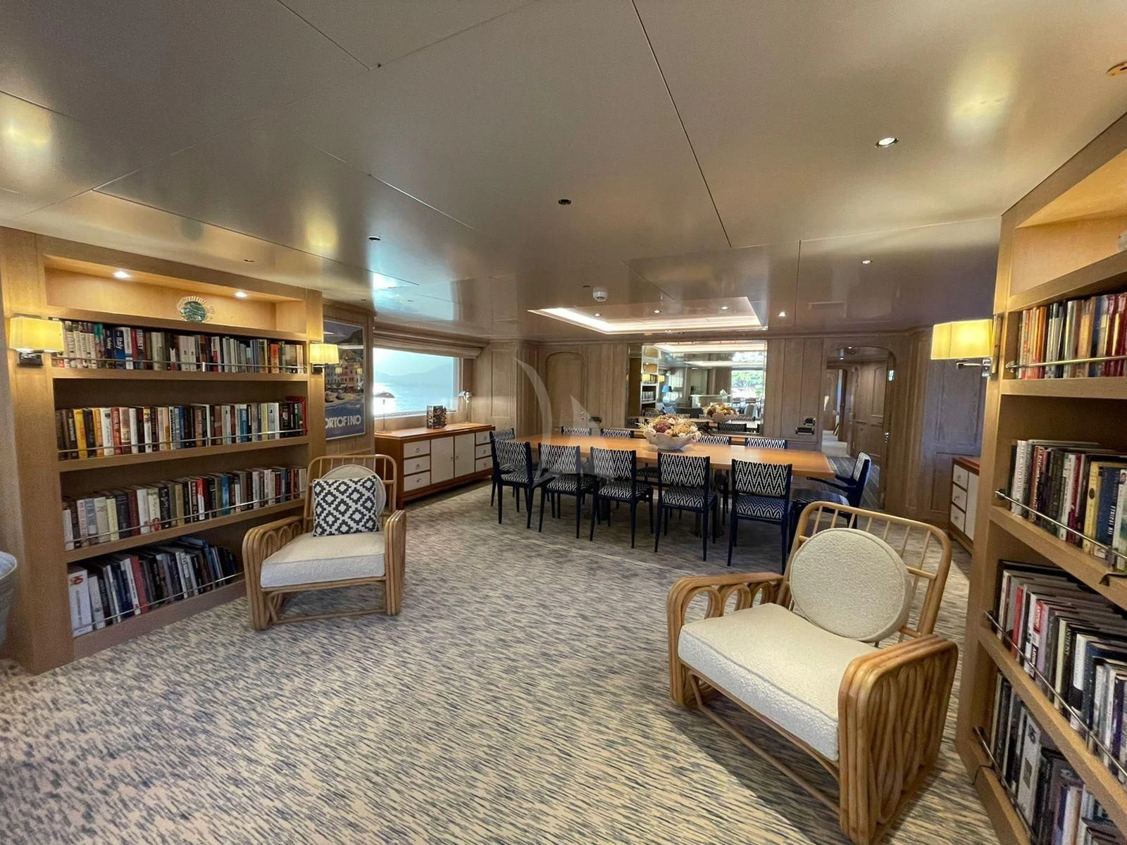 a room with a table chairs and bookshelves aboard NATALIA V Yacht for Sale