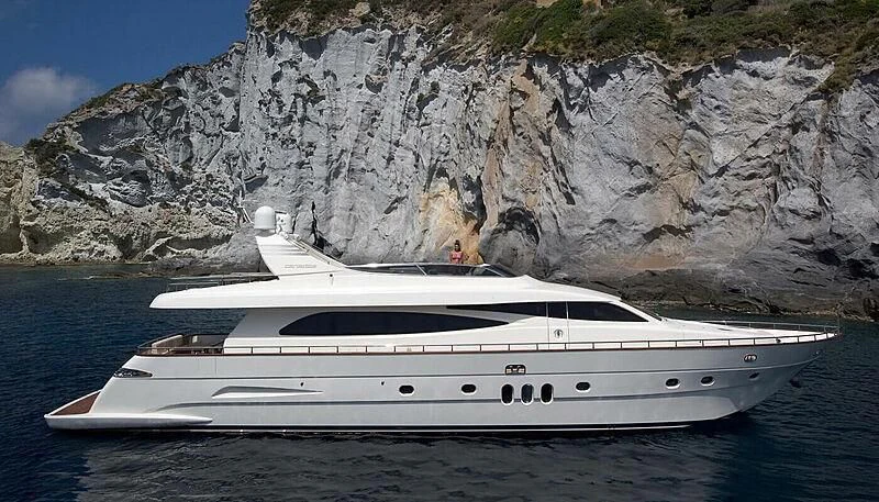 a white yacht in front of a rocky cliff aboard HABANO Yacht for Sale
