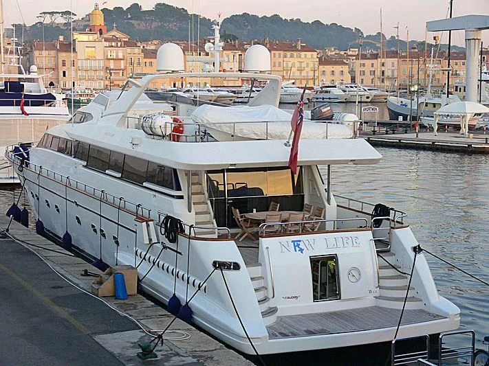 a boat docked at a pier with HMS M33 in the background aboard LUMINOUS Yacht for Sale