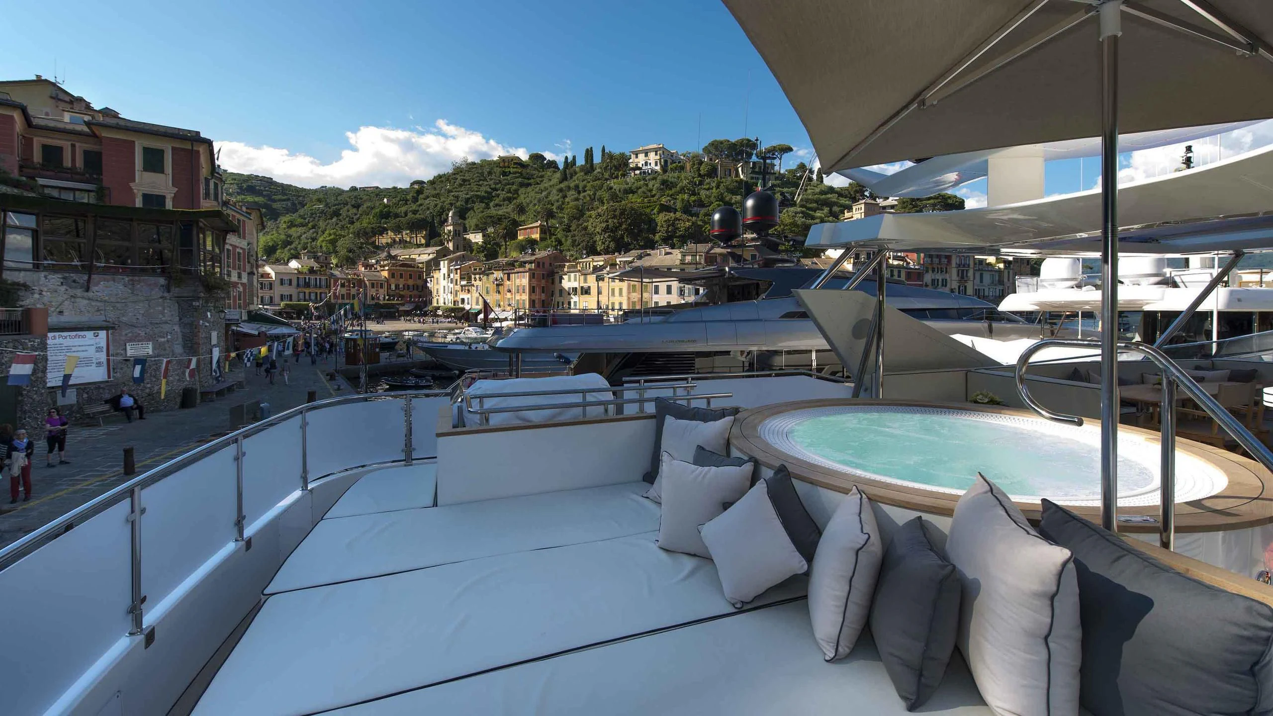 a large lounge area with a pool and buildings in the background aboard LUMINOUS Yacht for Sale