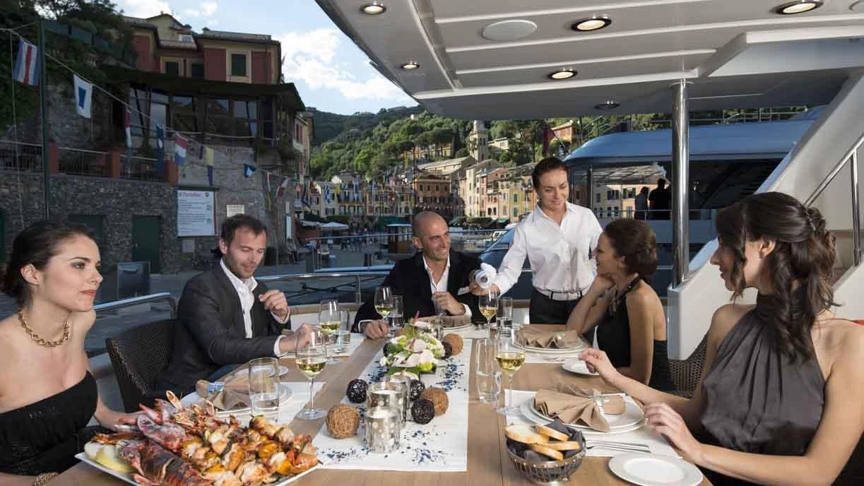 a group of people sitting at a table with food and drinks aboard LUMINOUS Yacht for Sale