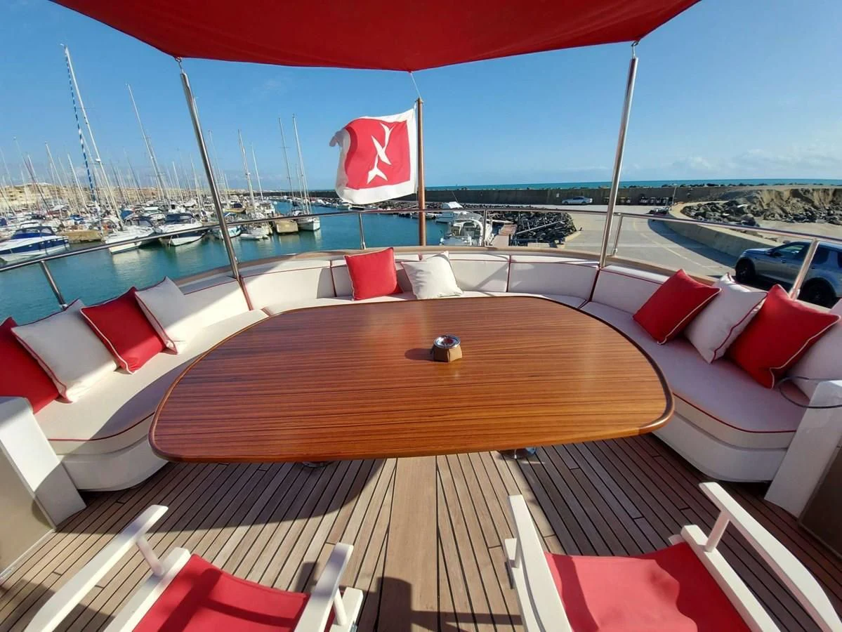 a deck with a flag and a body of water in the background aboard DENEB'S DAUGHTERS Yacht for Sale