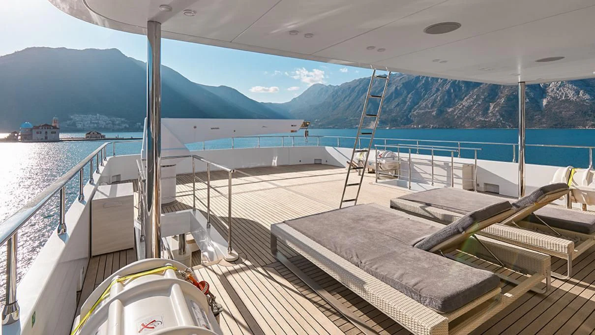 a deck with a view of the ocean and mountains aboard VERA Yacht for Sale