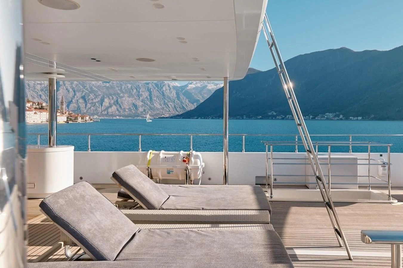 a deck with a view of a body of water and mountains in the background aboard VERA Yacht for Sale