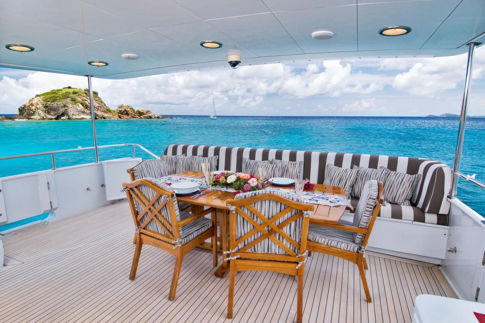 a table and chairs on a deck overlooking a body of water aboard THREE KINGS Yacht for Sale