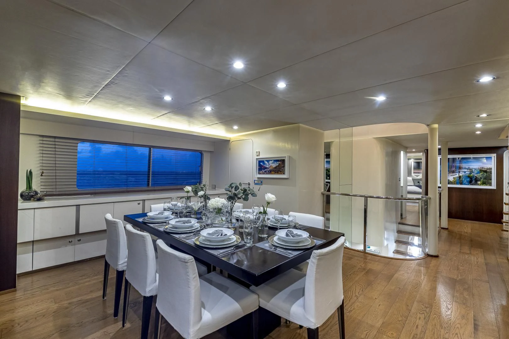 a dining table and chairs in a room with a large window aboard KARTAL YUVASI Yacht for Charter