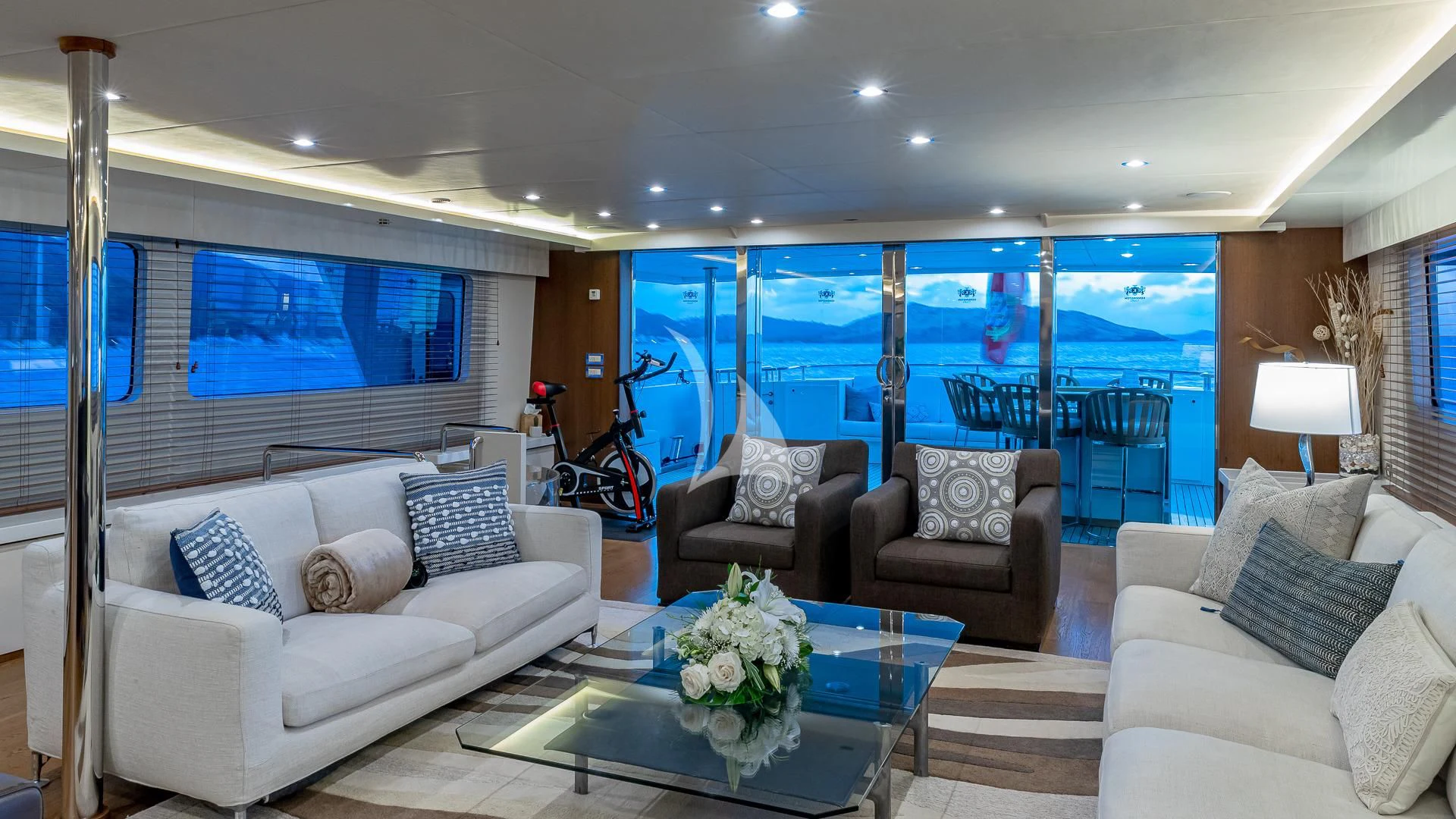 a living room with a large glass table and a view of the ocean aboard KARTAL YUVASI Yacht for Charter