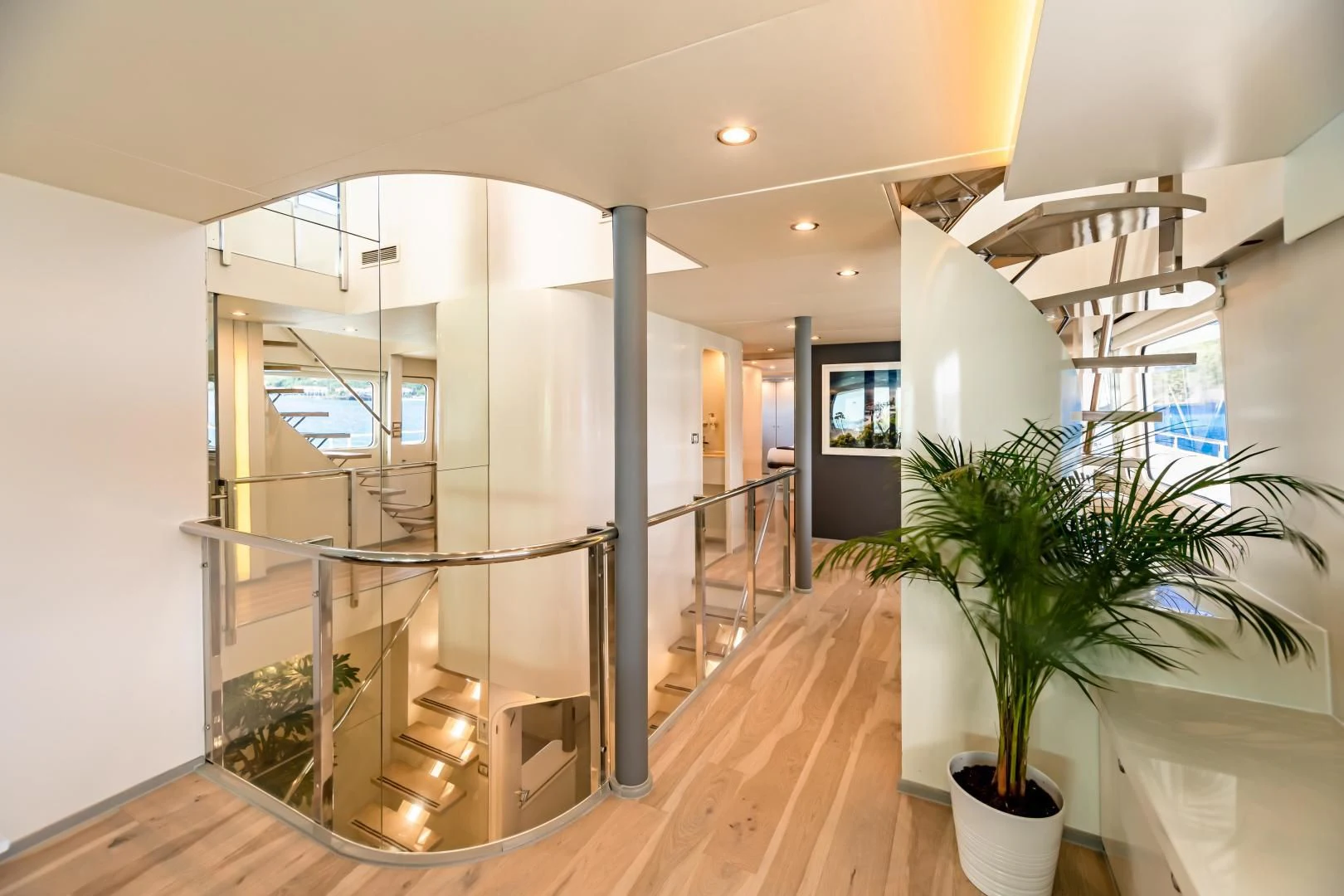 a large glass and metal staircase in a house with a potted plant aboard KARTAL YUVASI Yacht for Charter