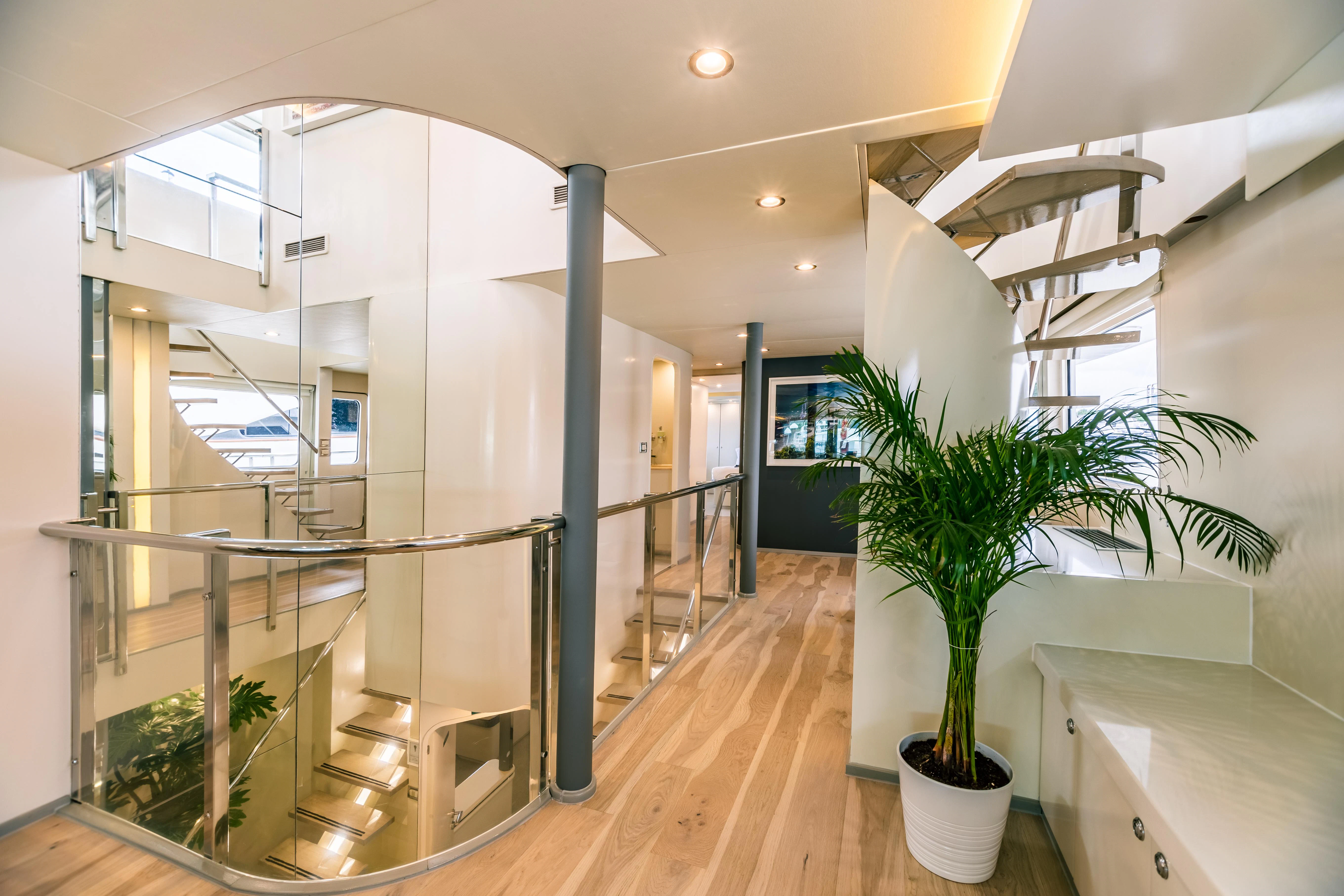 a large glass wall with glass doors and a plant in a pot on a wood floor aboard KARTAL YUVASI Yacht for Charter