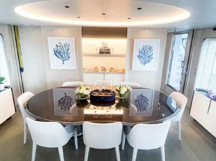 a dining table with chairs and a table with flowers on it aboard PENJA Yacht for Sale