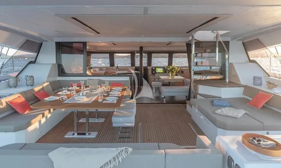 a room with a large window and a table with chairs and a couch aboard CHILOE Yacht for Charter